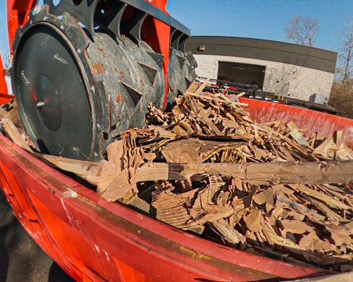 A Smash Truck® from Smash My Trash® performs mobile waste compaction on a red open-top dumpster.