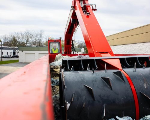 A Smash Truck® operator performing mobile waste compaction on an open-top roll-off dumpster.