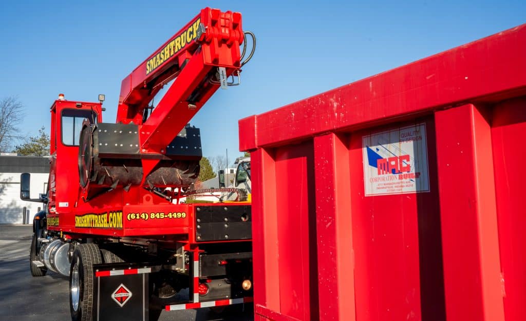 A Smash Truck® breaking up pallets in an open-top roll-off dumpster during mobile waste compaction service. 